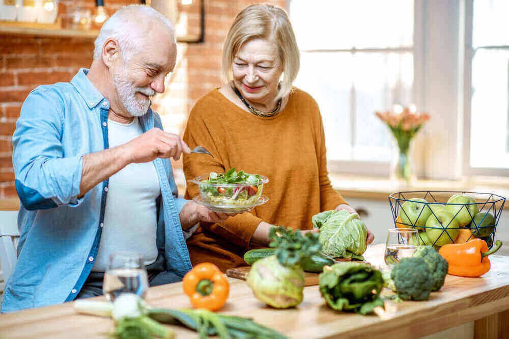Elderly couple preparing a healthy meal with fresh vegetables, promoting healthy ageing and lifestyle choices - How to Age Gracefully: Lifestyle Choices That Make a Difference - Windback NZ