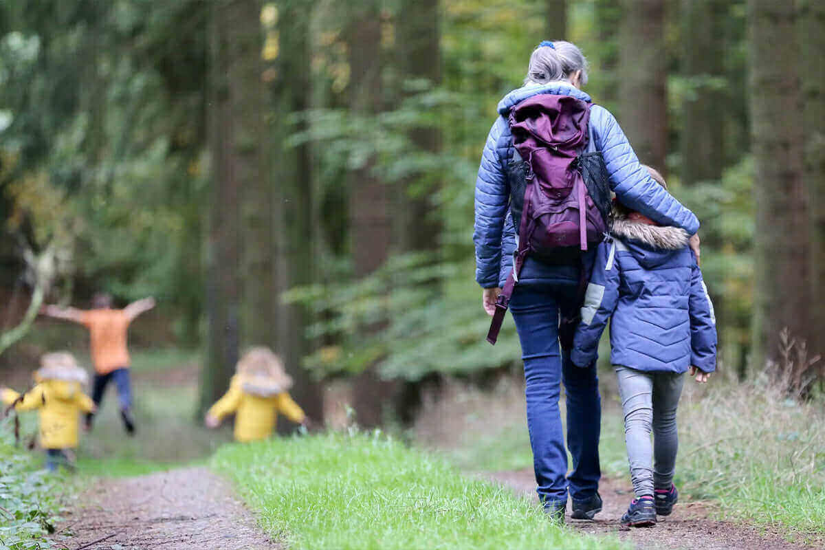 Family enjoying a walk in the woods with children playing, highlighting connections to nature and wellness - Windback NZ