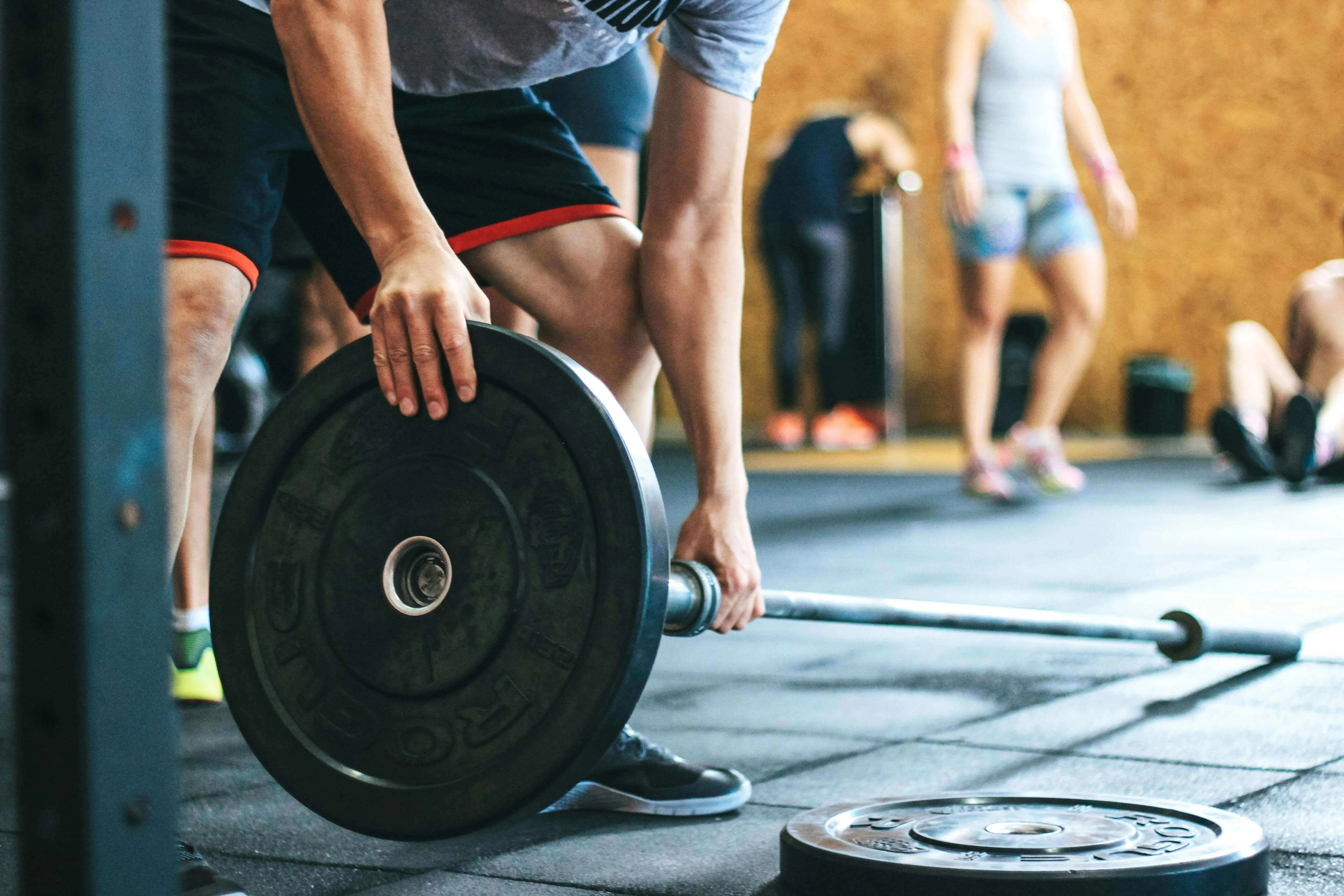 Person lifting weights in a gym, highlighting strength training in Stronger For Longer: Muscle, VO₂ Max and the New Markers of Healthy Ageing.