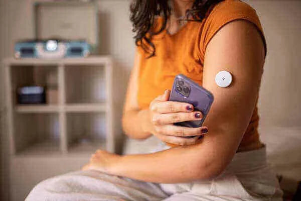 Person using a smartphone with a continuous glucose monitor on their arm to manage prediabetes early action: why it matters.