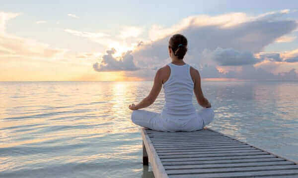 Person meditating by the water during sunset, embodying the Science of Breath: How Breathing Shapes Focus and Brain Health - Windback NZ.