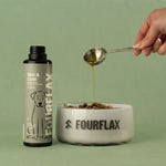 Fourflax pet product being poured into a bowl with a spoon on a green background