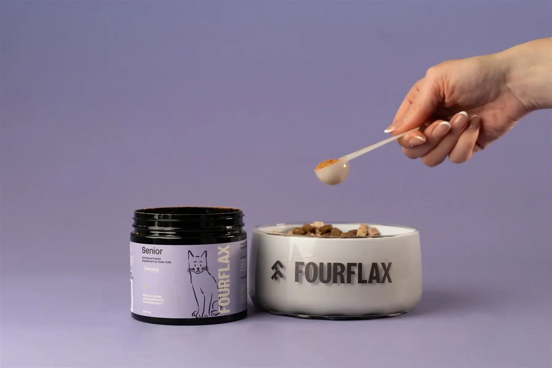Person scooping Fourflax pet food from a bowl with a jar of Fourflax product on a purple background